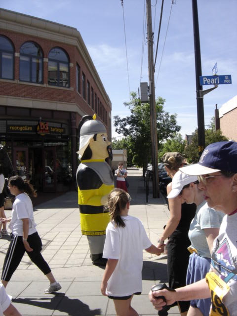people are walking by a street in front of a large statue of a bee