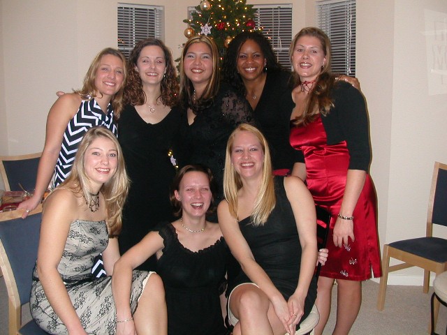 a group of women pose together next to a christmas tree