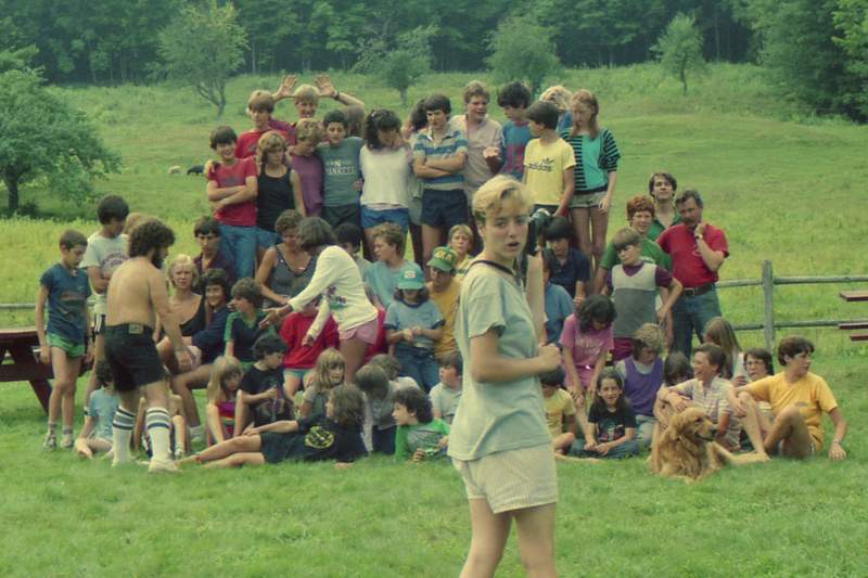 a group of children gathered around a dog in front of people