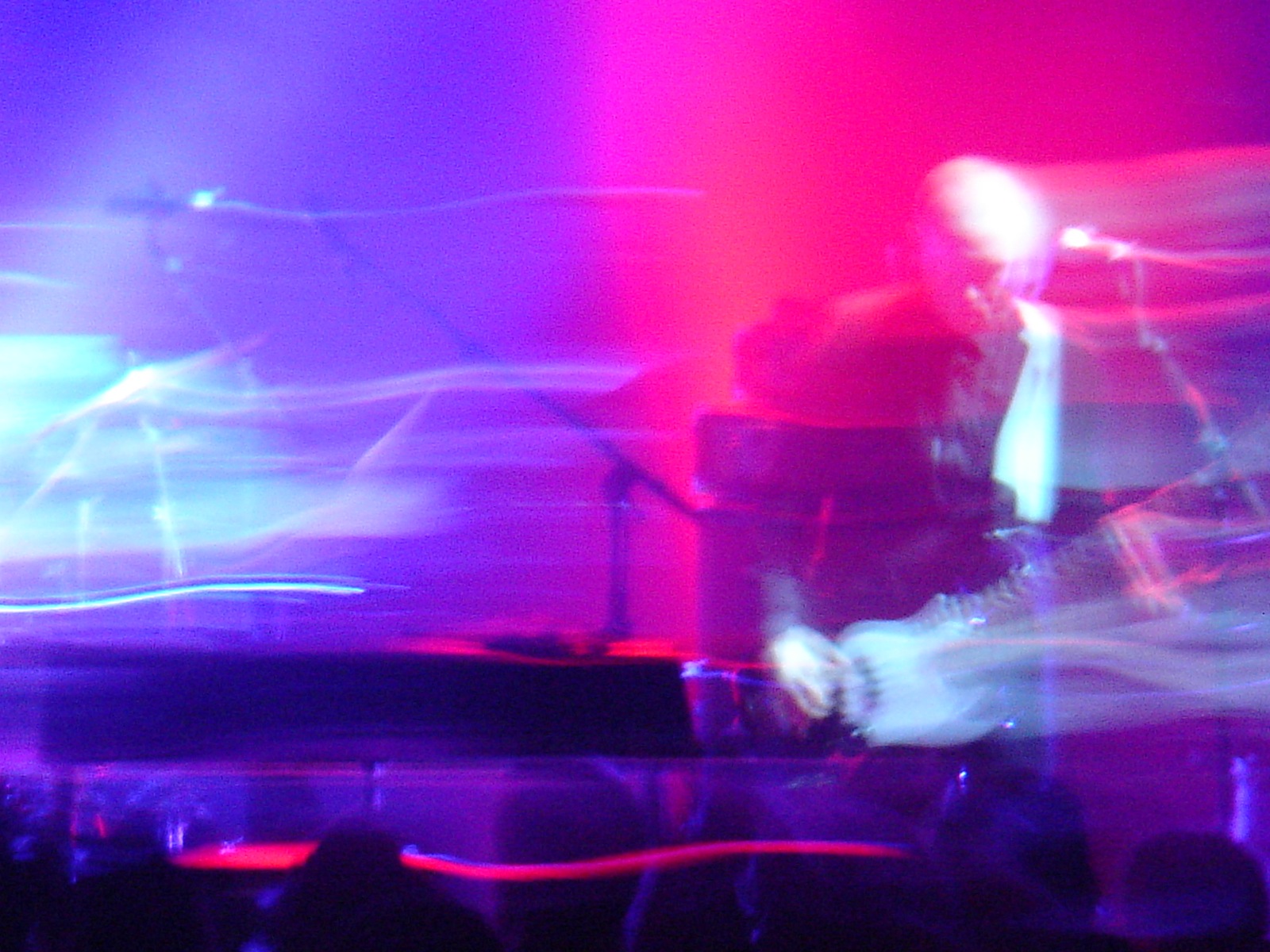 a blurry image of people on a concert stage playing guitars