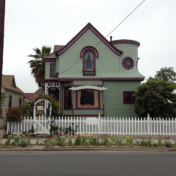 green victorian - style house with window and shutters along street
