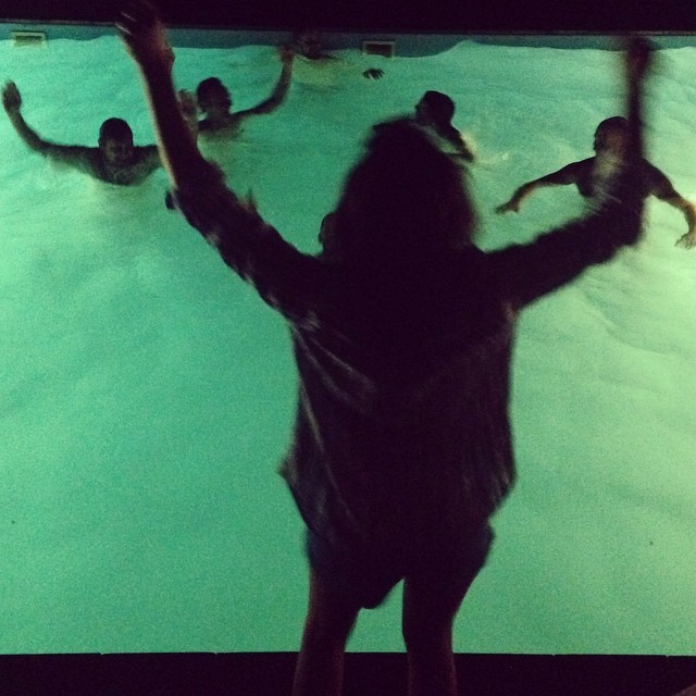 a woman watching people in a pool in a darkened area