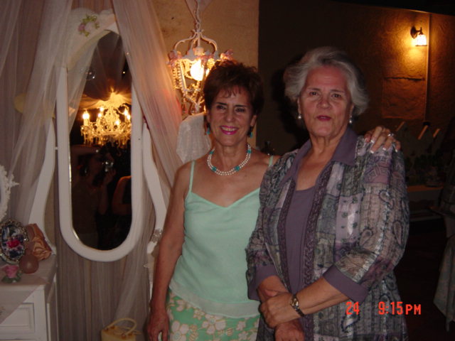 two women standing next to each other in front of a chandelier
