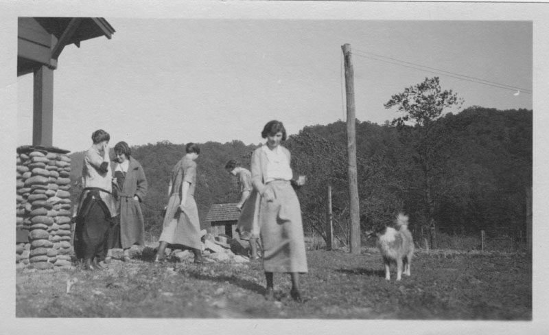 old pograph of ladies standing by a house with their dog