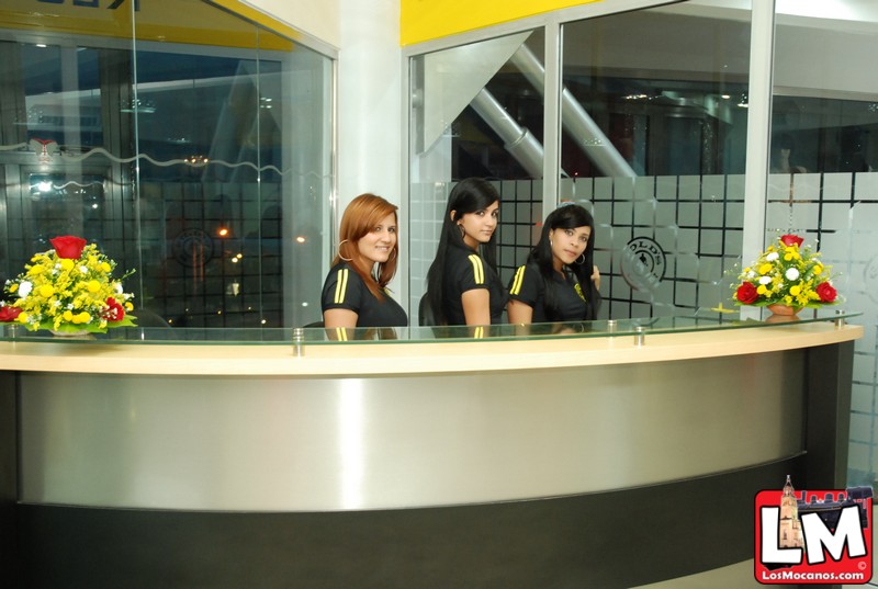 three young women sitting behind a counter next to a wall