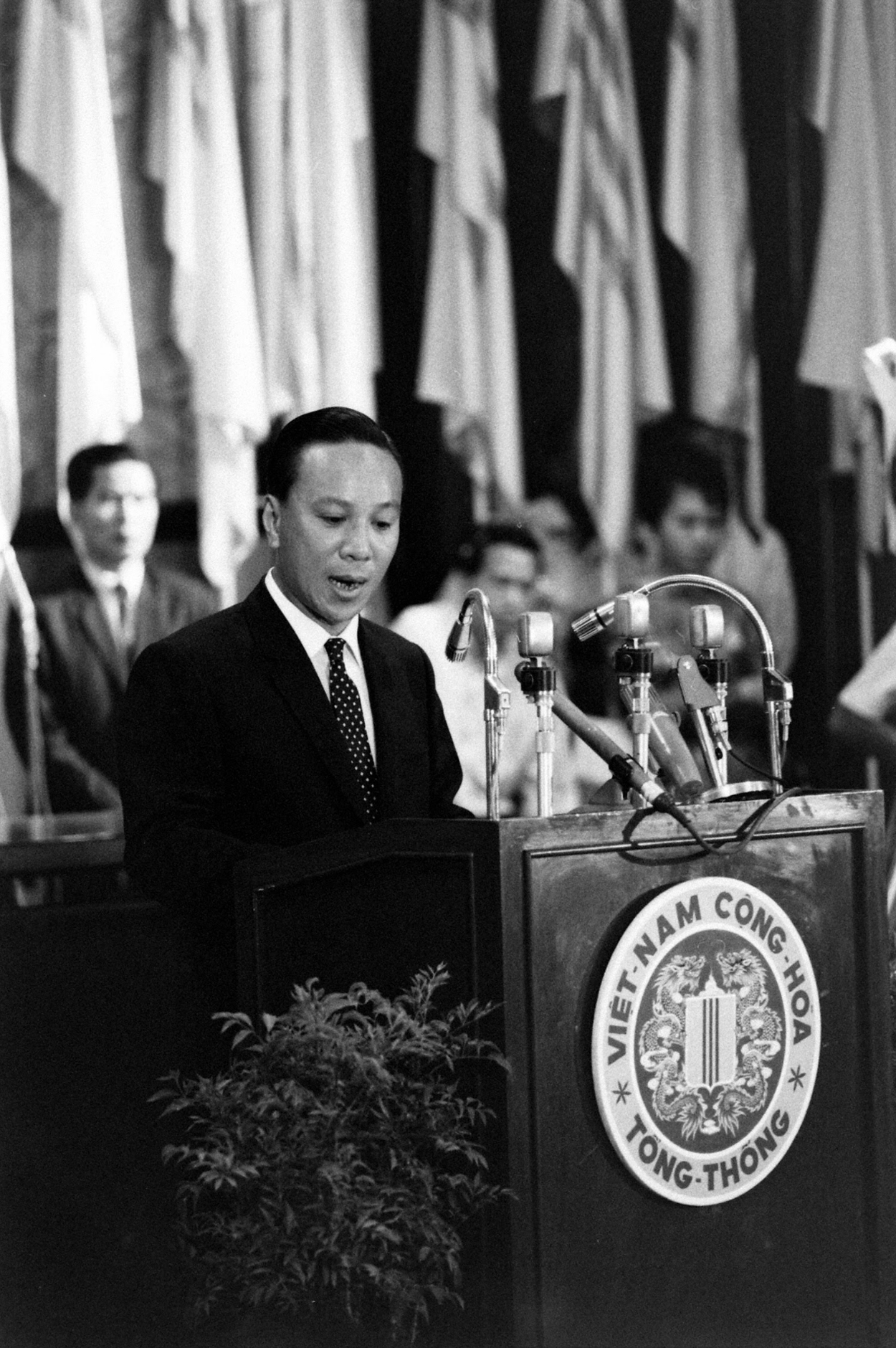 a man in suit speaking at a podium in front of an audience