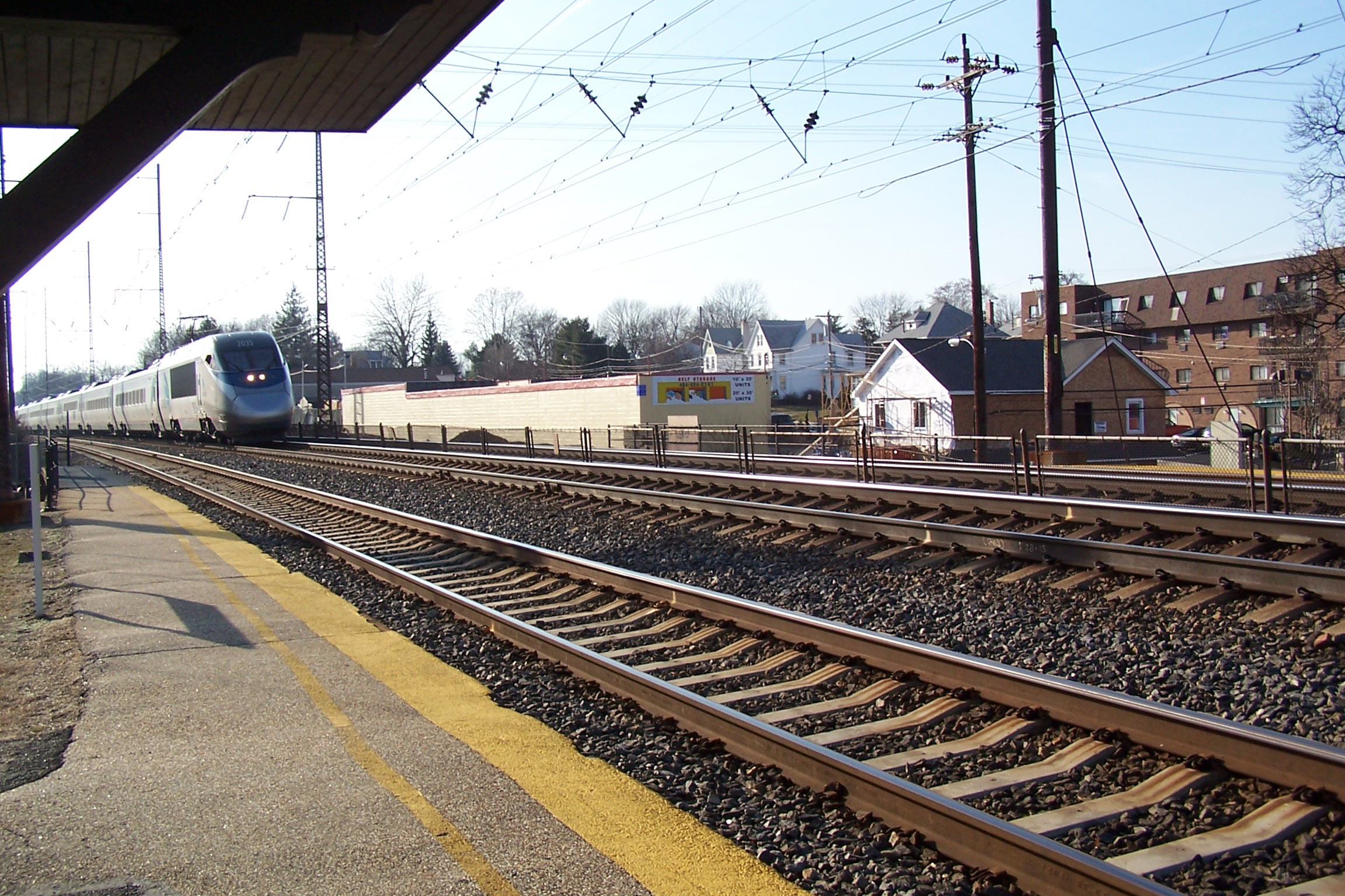 train coming down the tracks with a row of buildings in the background