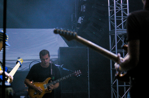 two men standing on a stage with guitars