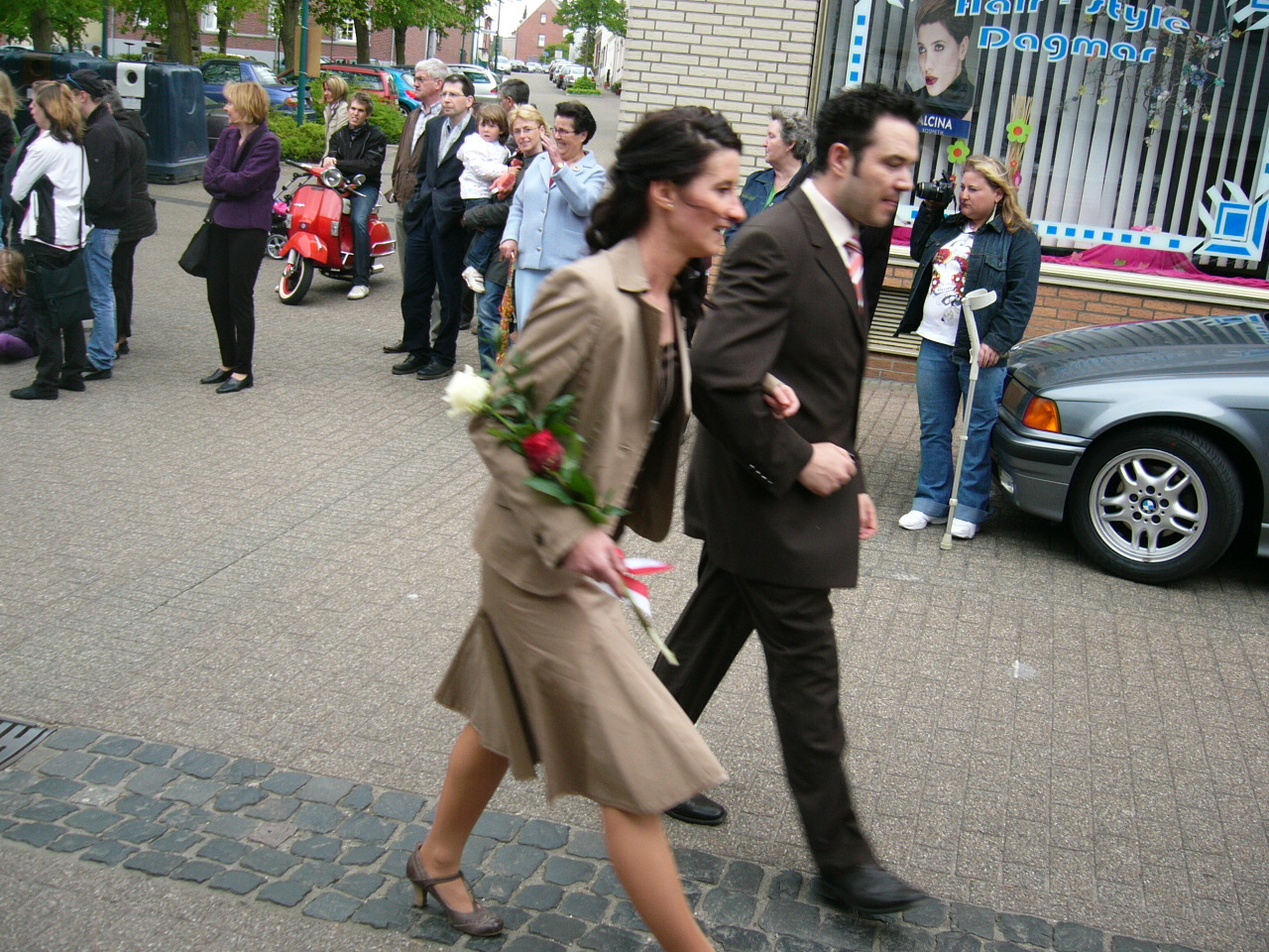 a man and woman dressed in formal attire walk side by side down the street