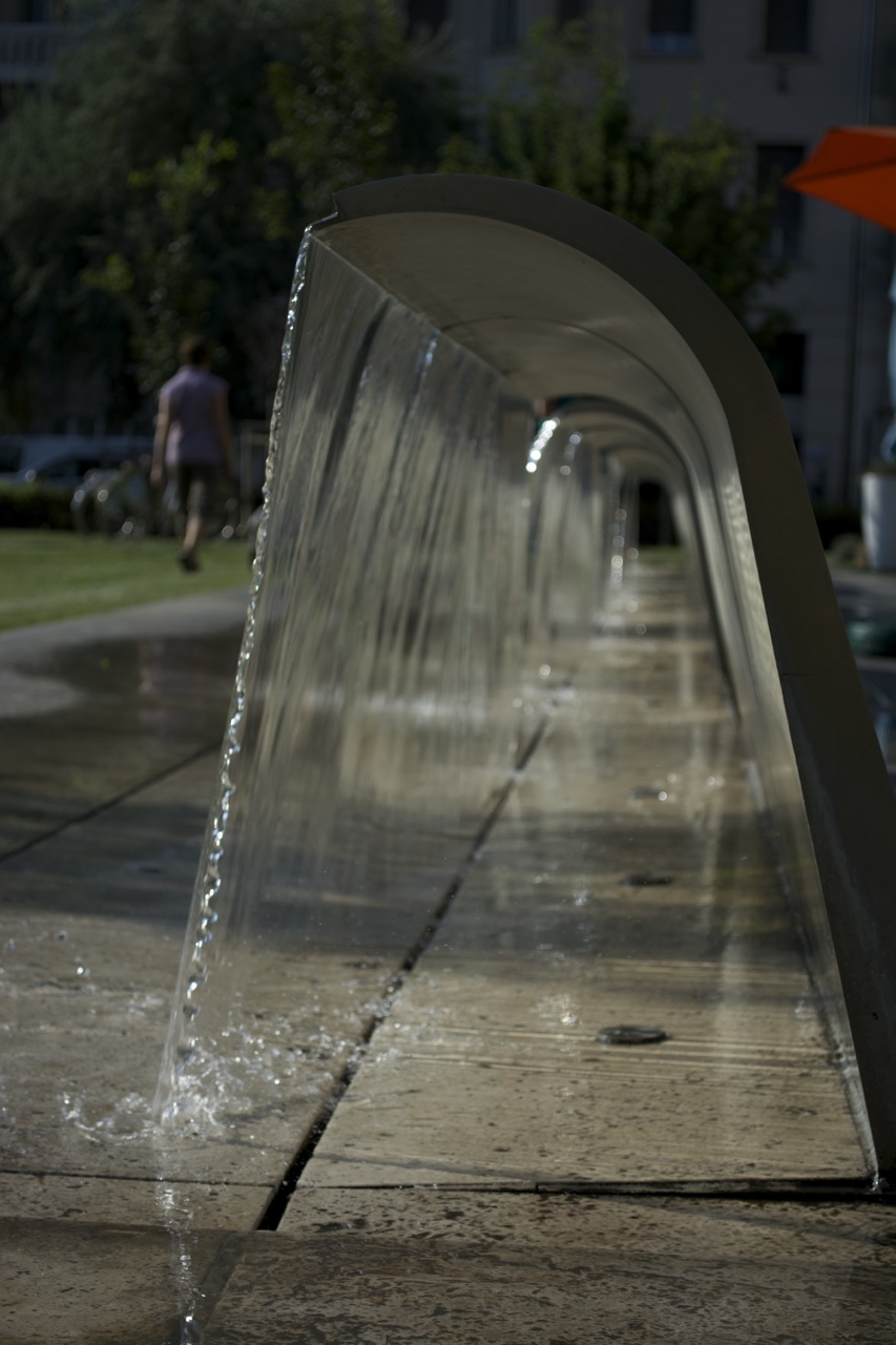 a row of water spouts from a large, long metal fountain