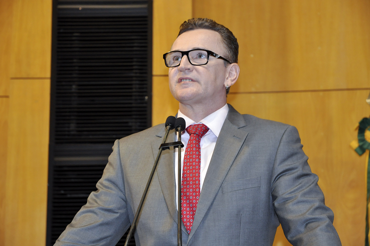 the man wearing glasses and a red tie has a microphone in front of him