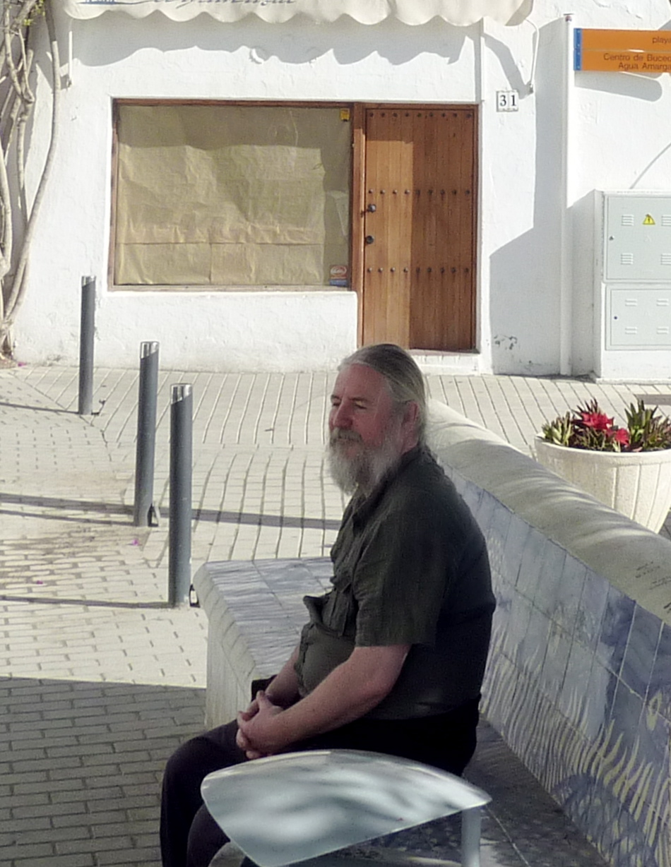 man with white hair and beard sitting on the bench