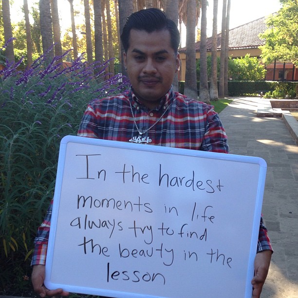 a man holding a sign that reads in the harbess movements in life always try to find the beauty in the lesson