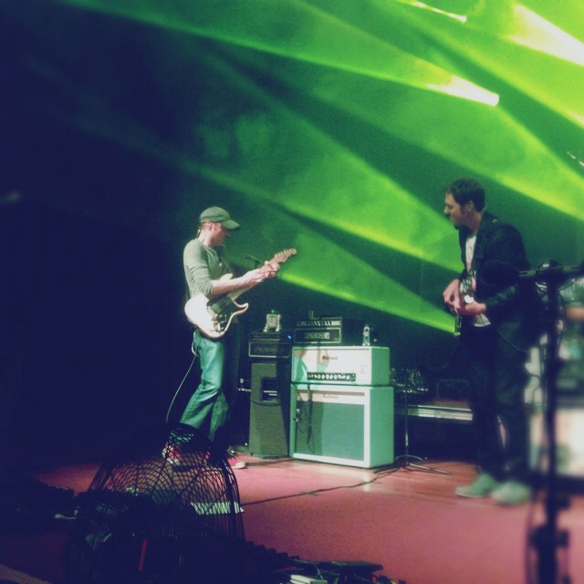 two men standing on a stage while playing guitars