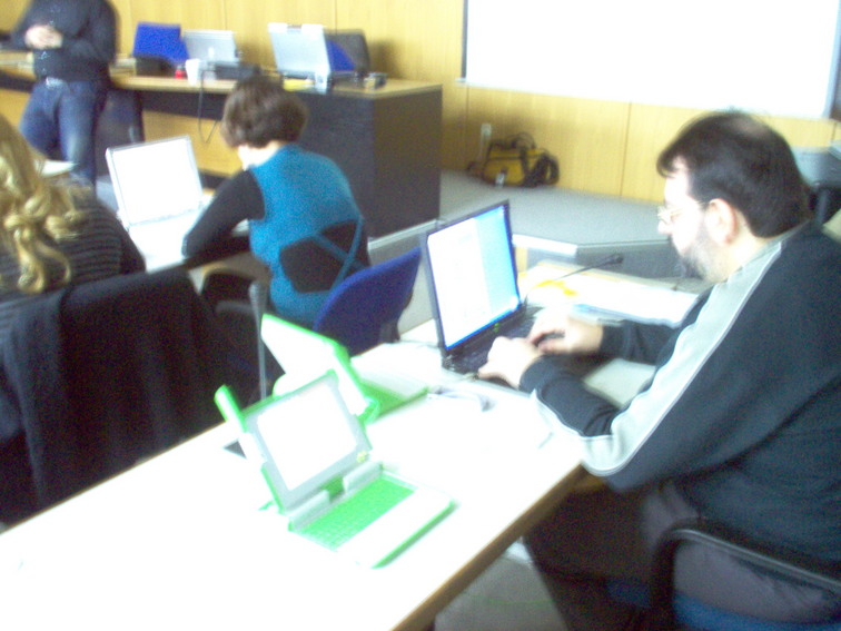 people sit at a table using computers in an office