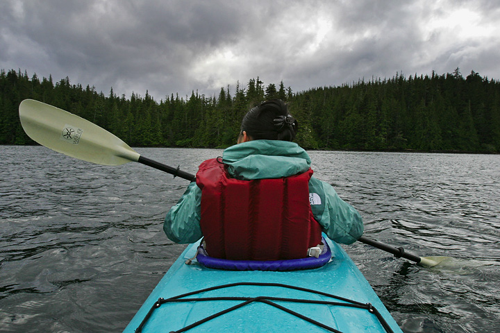 a person paddling on the water in a kayak with trees around