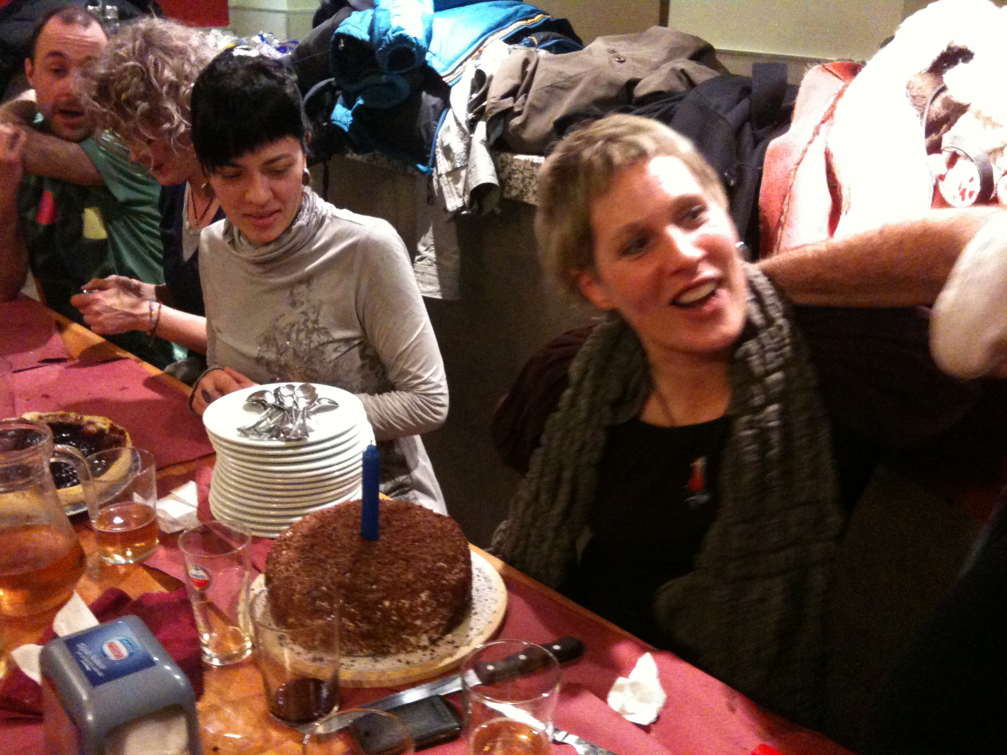 a bunch of people gathered around a table with a cake and candles