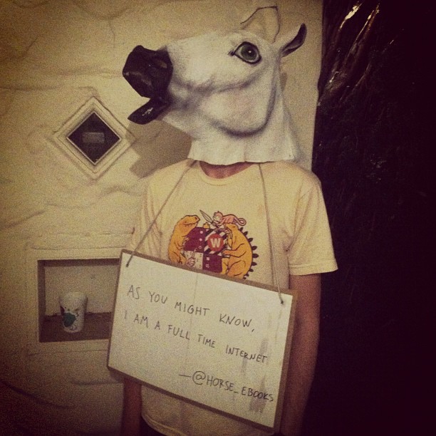 a person wearing a cow mask with a sign on it