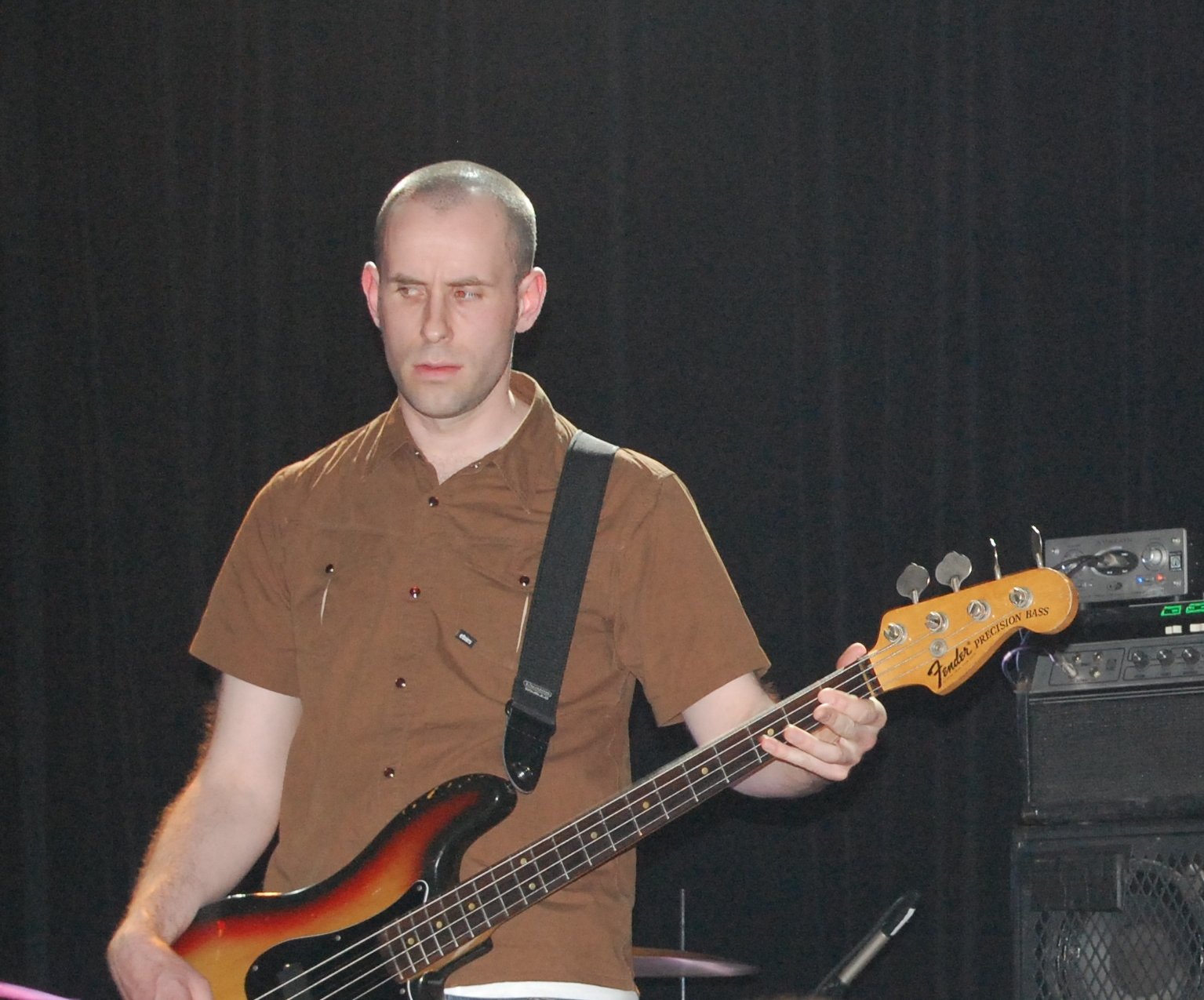a man holding up a guitar and wearing a brown shirt