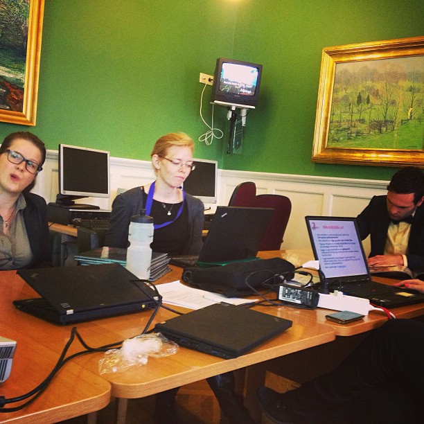 a group of people working on laptops around a wooden table