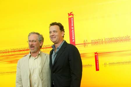 two men stand together in front of a yellow background