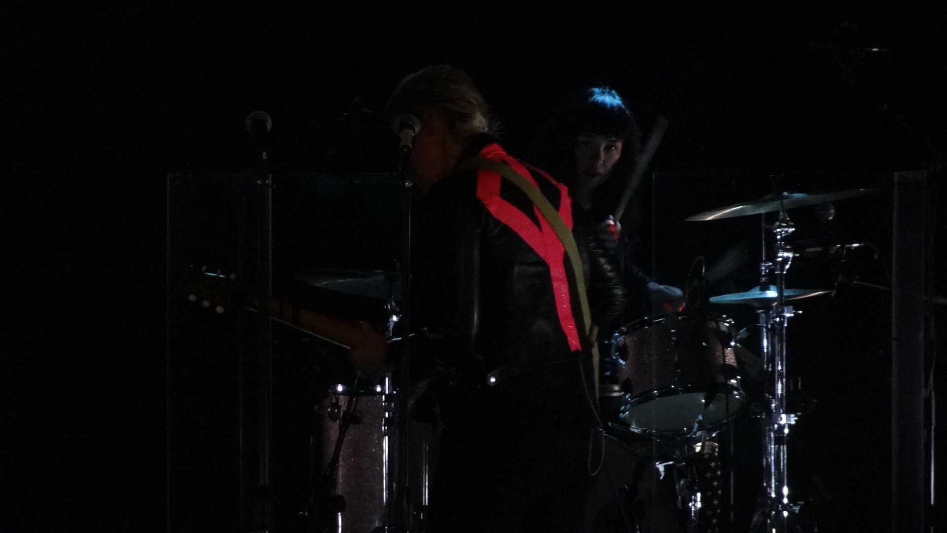 two people with drums and microphones on a stage