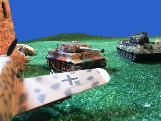 several toy army tanks and an aircraft on grass
