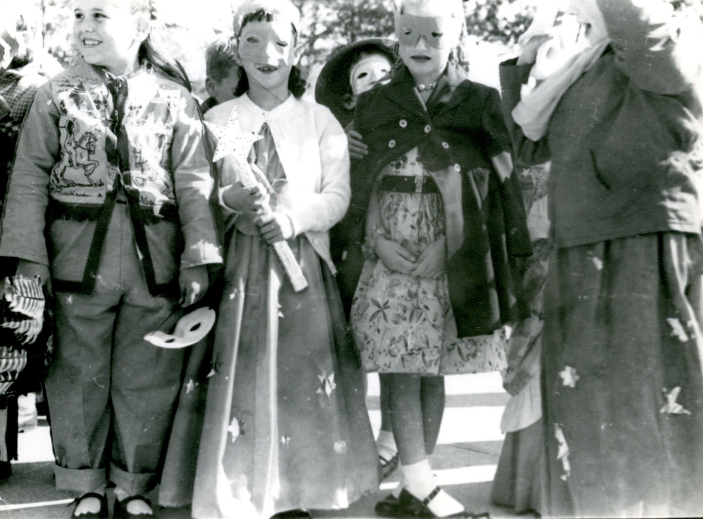 a black and white image of two men wearing long coat standing next to three women