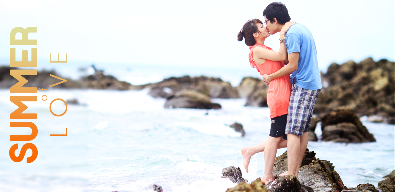 a young man and woman standing on a rock next to the ocean