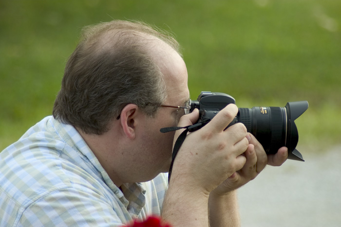 a man with glasses taking a picture with his camera