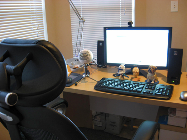 a desk with a computer, keyboard, and many stuffed animals