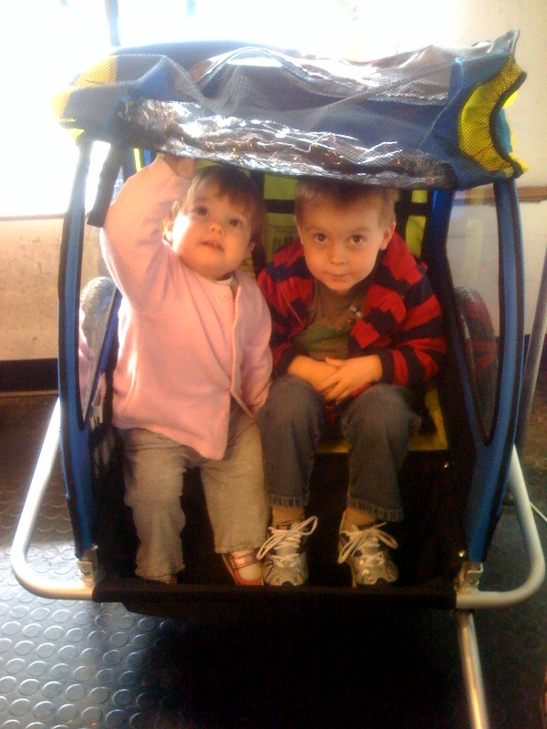 two children sitting on a child's toy car