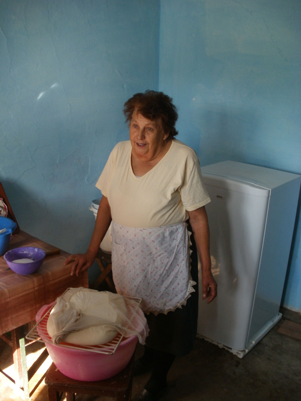 an older woman standing behind some food in a pink basket