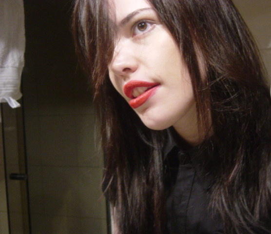 a girl with red lipstick holding onto a bathroom mirror