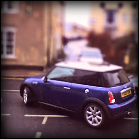 a car driving on the street with houses in the background