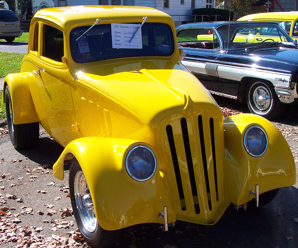 an old yellow classic car with no hoods is parked on a street