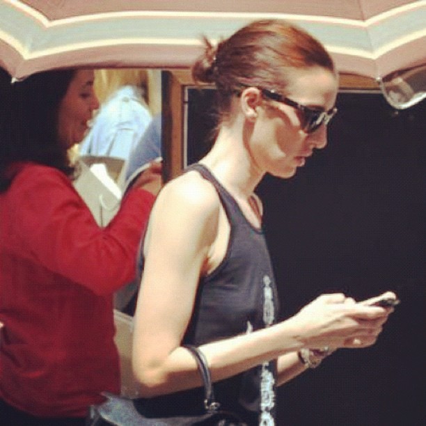 a young lady is texting and carrying a bag