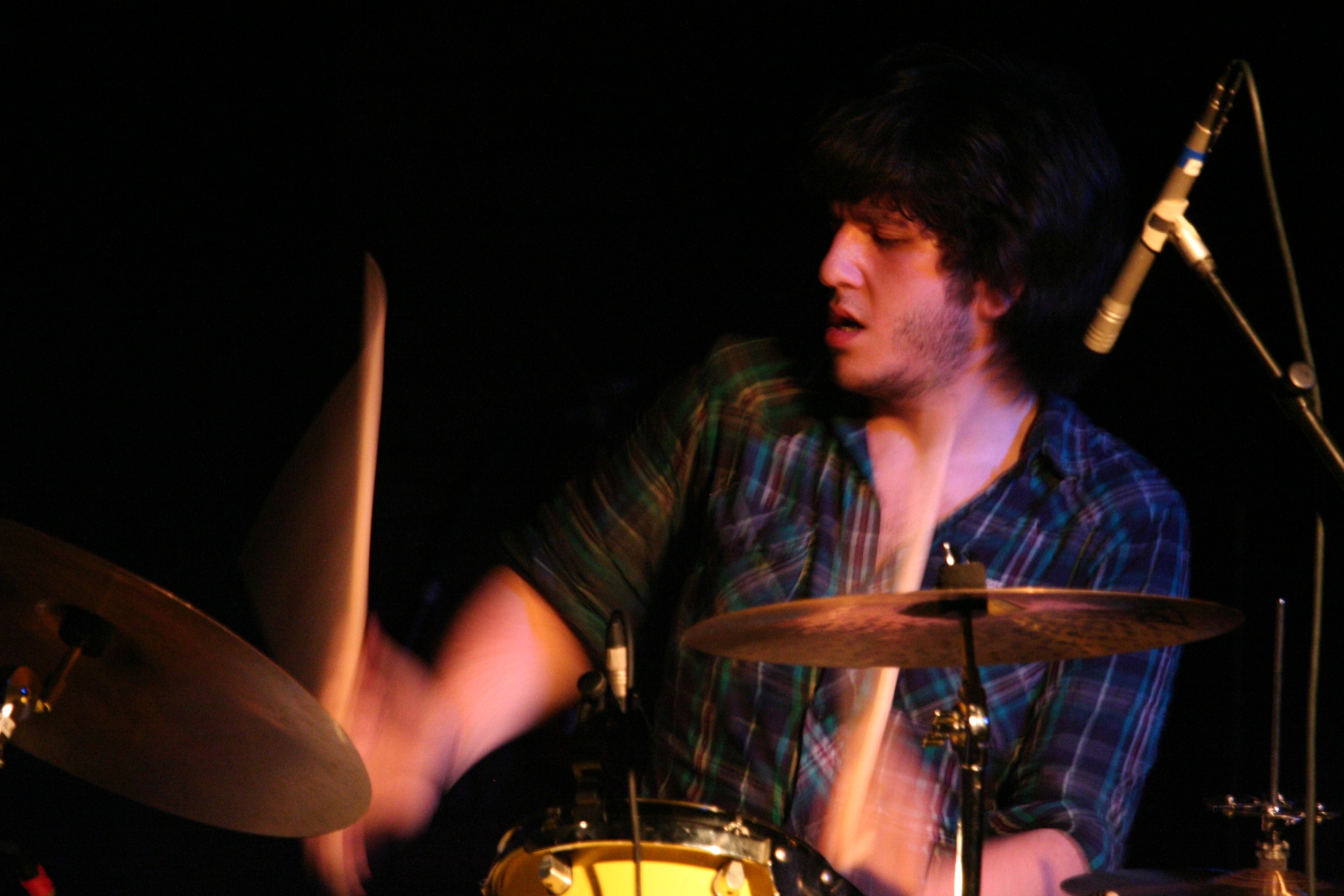 the man is playing with the drums in front of his microphone