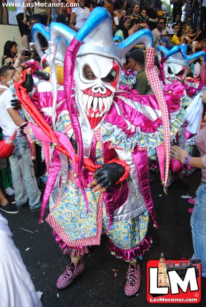 a man in costume walking down a street during a carnival