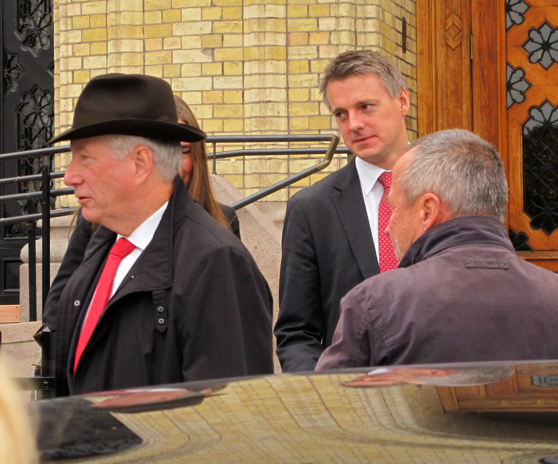 three men in suits, ties and hats outside