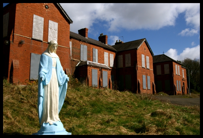 the statue stands next to a very large brick house