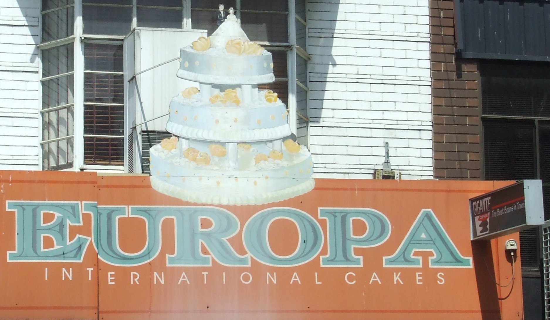 there is a very tall cake sitting on the sign