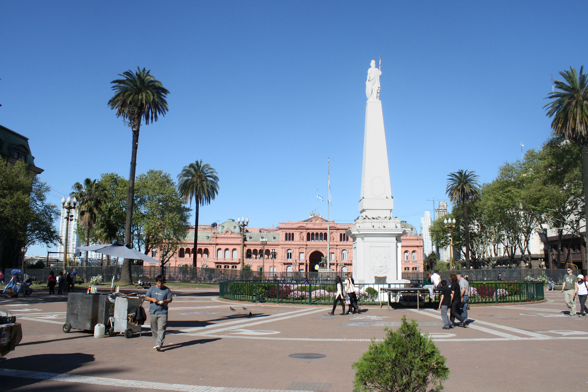 the people are standing around the obelisk statue