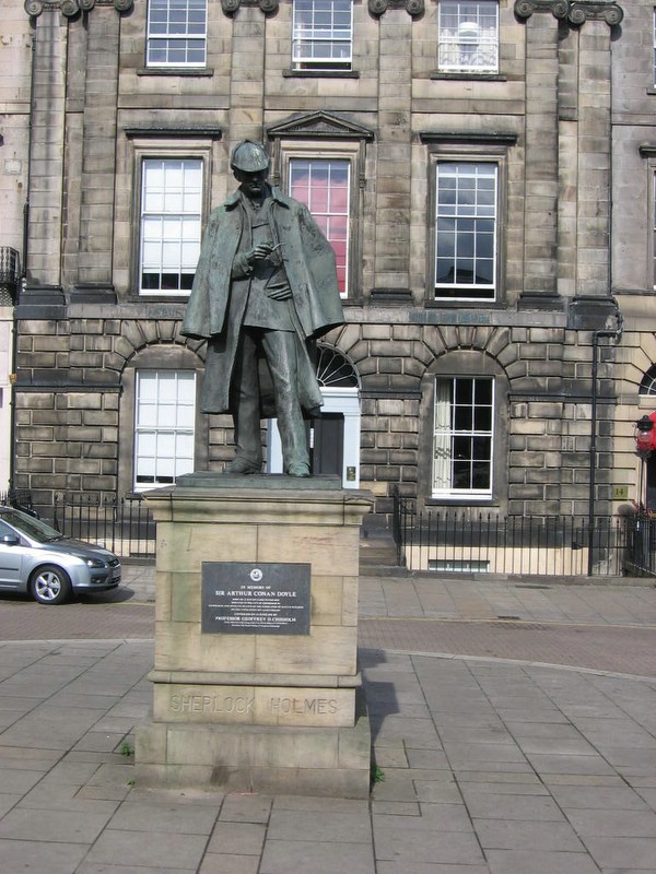 a statue of a man with a hat in front of a building