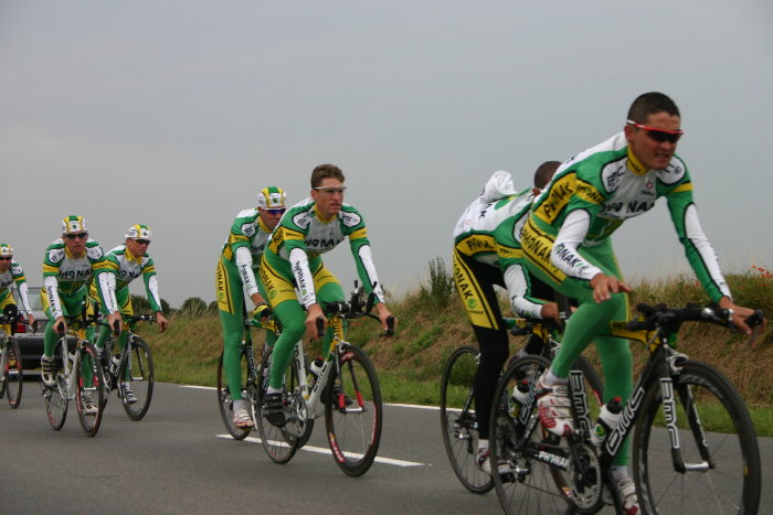 a group of cyclists riding down the road