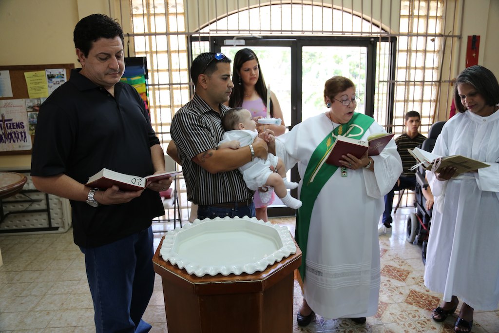 priest and two women with child in a church