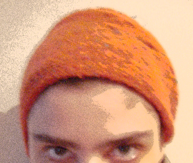 an orange knit hat covering someone's face and smiling