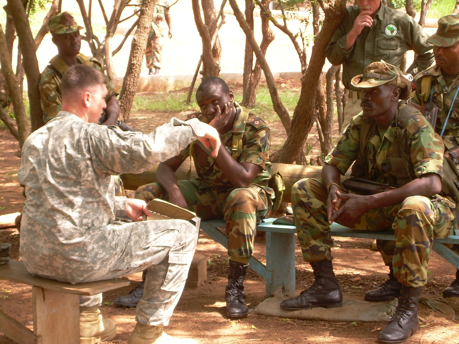 the soldier is holding up his hand as people sit on benches