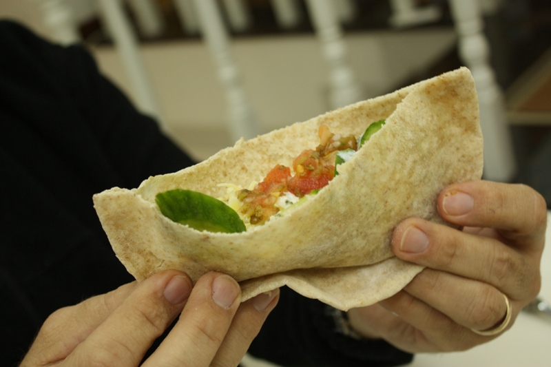 a hand is holding a burrito with a toothpick in it