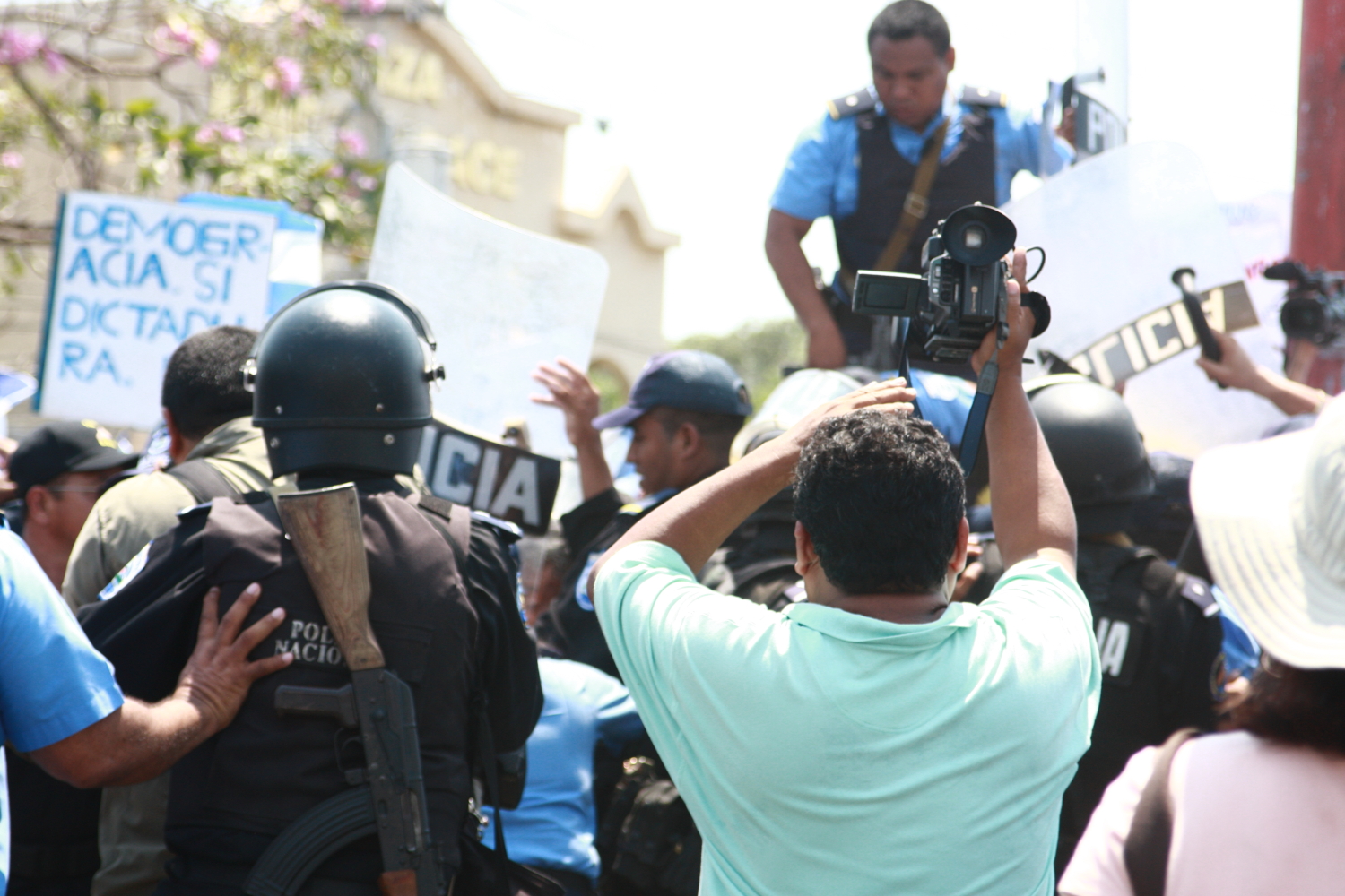 police officer with camera recording protest in city